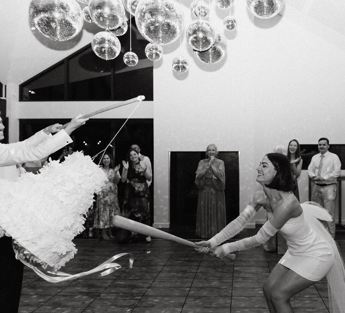 Piñata wedding cake alternative being smashed by bride and groom
