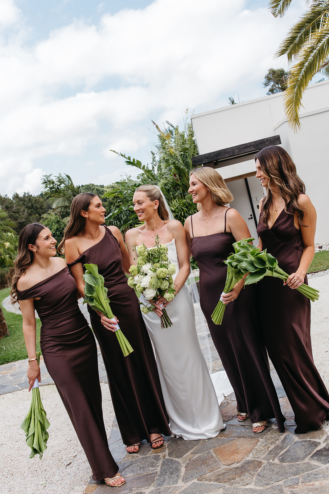 Bridesmaids wearing brown Bec and Bridge dresses holding unique green bouquets
