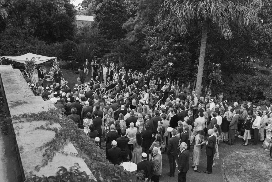 Jewish Bedekken ceremony moment with bride and groom surrounded by family in garden setting
