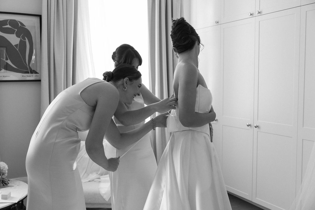 Bride getting dressed in Karen Willis Holmes two-piece wedding dress with bridesmaids
