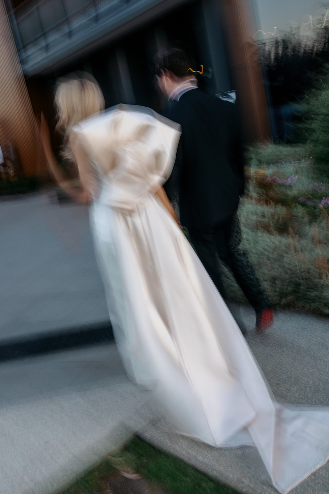 Motion blur candid of bride and groom walking together at Marnong Estate Winery, Melbourne, bride's custom silk wedding gown with statement back bow captured in movement photography by Kinship by Kristy