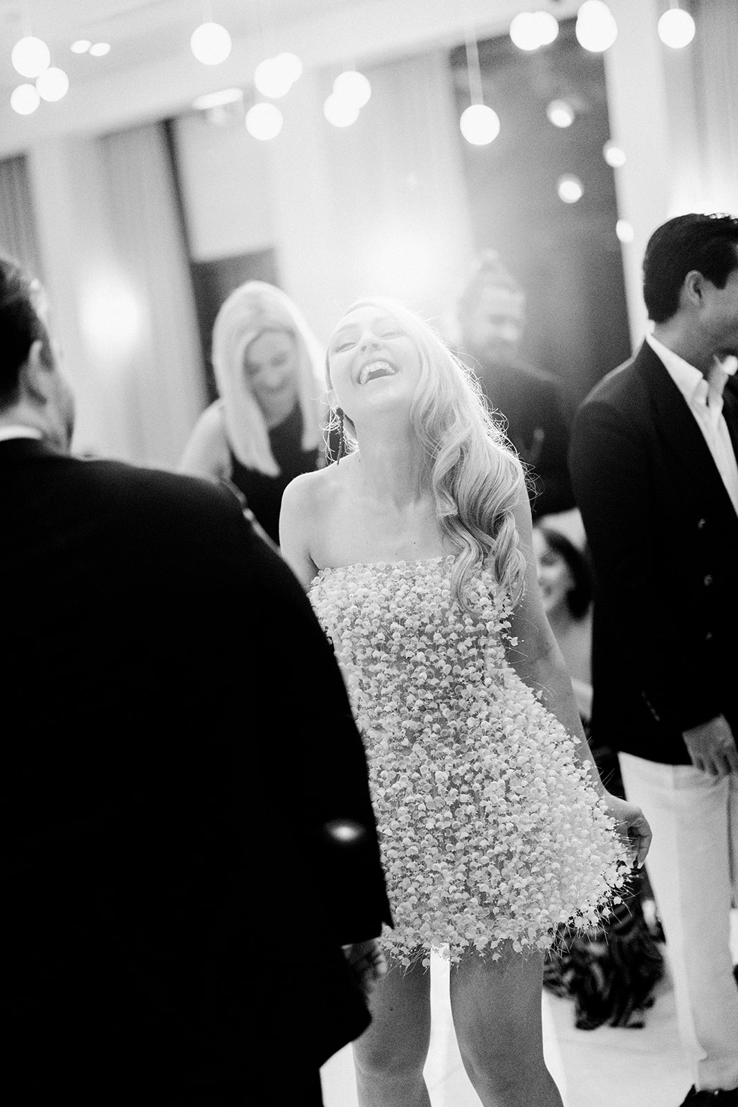 Black and white candid of bride laughing on the dance floor at her Melbourne winery wedding reception wearing a short white floral appliqué dress. Marnong Estate Winery, photography by Kinship by Kristy