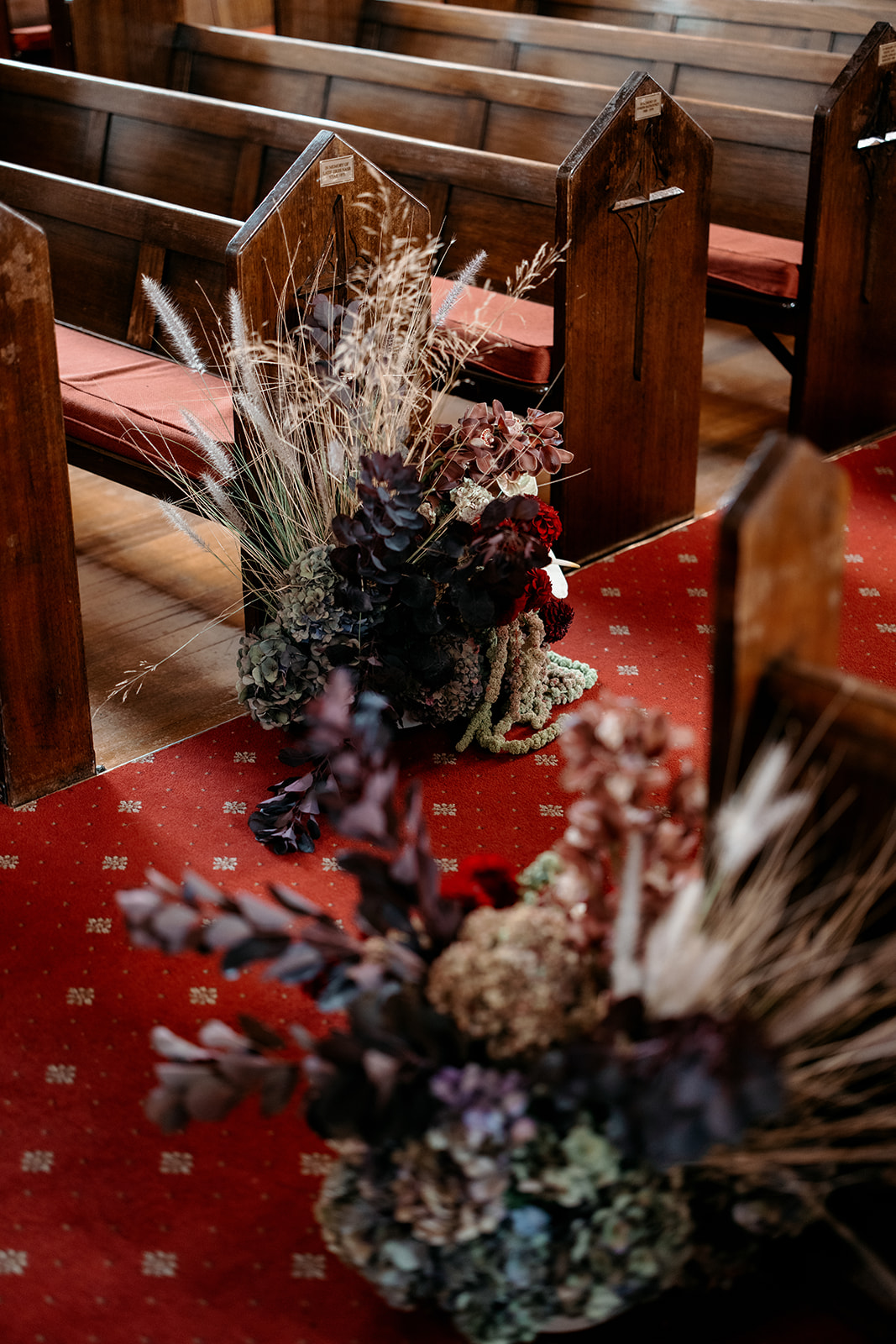 Dried and fresh floral ceremony arrangement in burgundy, blush and dusty tones styled along church pews at a Melbourne Lebanese wedding – florals by The Beautiful Bunch, photography by Kinship by Kristy
